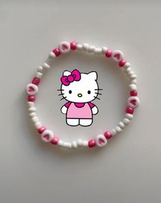 a hello kitty bracelet with pink and white beads on the end, sitting on a table