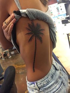 a woman with a palm tree tattoo on her lower back and right side ribcage