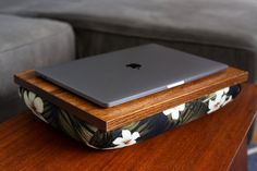 an apple laptop sitting on top of a wooden table in front of a gray couch