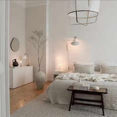 a bedroom with white walls and flooring has a large bed in the middle, surrounded by candles