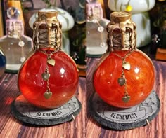 two red vases sitting on top of a wooden table next to each other with charms hanging from them