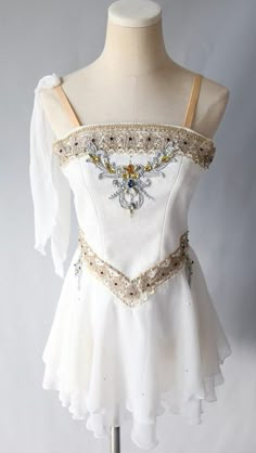 a white dress on a mannequin with gold trimmings and beading