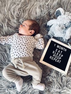 a baby laying next to a teddy bear and a sign that says 1 month left sleep repeat repeat