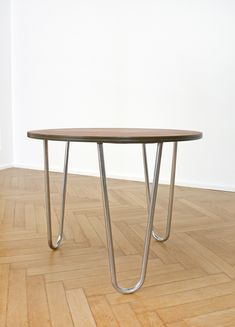 a wooden table sitting on top of a hard wood floor next to a white wall