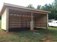 a white truck is parked in front of a shed with two stalls on the grass