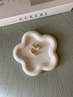 a white flower shaped object sitting on top of a table next to a boxed box