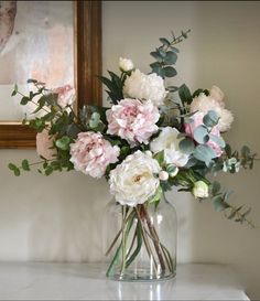 a vase filled with pink and white flowers sitting on top of a table next to a mirror