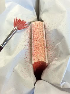 a brush is sitting on top of a piece of paper with red sprinkles