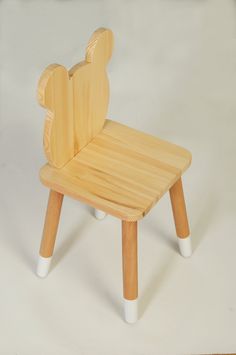 a wooden chair with white legs and a bear head on the backrest, sitting in front of a white background