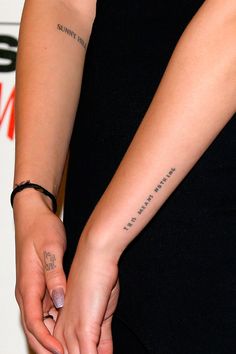 a woman's hands with tattoos on her left arm and the word love is written on