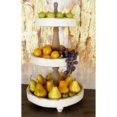 three tiered tray with fruit displayed on top of each other in front of an old wall