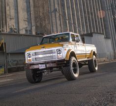 a yellow and white truck parked on the side of a road next to a tall building