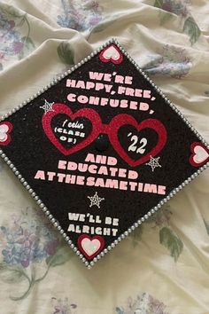 a graduation cap with hearts on it sitting on top of a bed covered in flowers