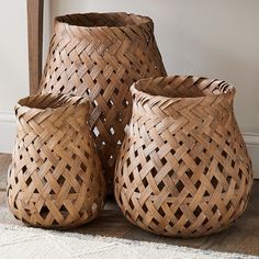 three woven baskets sitting on top of a wooden floor