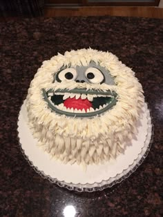 a cake with white frosting and a monster face on it sitting on a counter