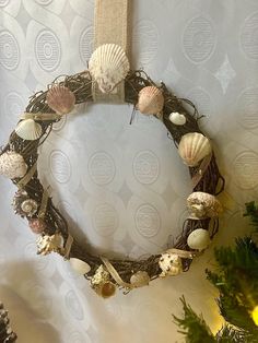 a wreath with seashells is hanging on the wall next to a christmas tree