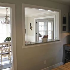 an empty kitchen and dining room are reflected in the mirror on the wall above the counter