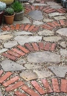 a stone path with potted plants on either side and gravel in the middle between them