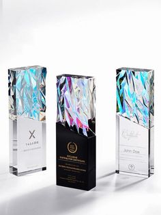 three award plaques with different designs and colors on them, one is black, the other is white