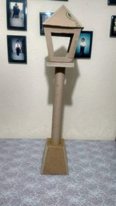 a bird feeder made out of toilet paper on top of a carpeted floor next to pictures