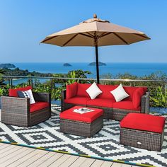 an outdoor patio with blue furniture and an umbrella over the seating area overlooking the ocean