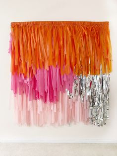 an orange and pink wall hanging on the side of a white wall