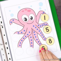 a hand is holding a sticker with numbers on it and an octopus in the middle