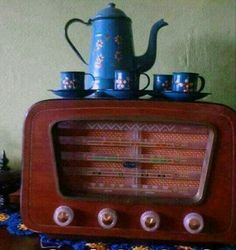 an old fashioned radio sitting on top of a table with cups and teapots