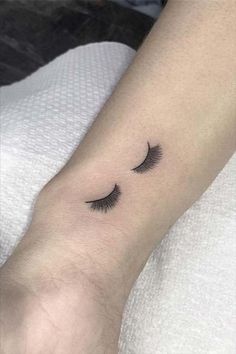 a woman's arm with a small tattoo on it that has eyelashes drawn across the wrist