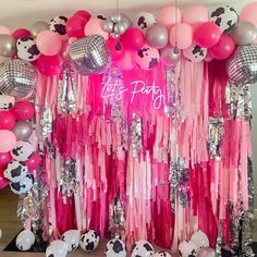 a pink and silver party with balloons, streamers, and cow print wall hangings