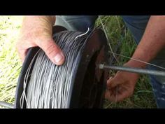 a man is holding a spool of wire in his hand while another person works on it