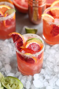 blood orange margaritas are garnished with lime and sliced grapefruit on ice