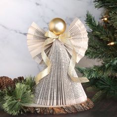 an ornament made out of folded book pages with a golden ball on top