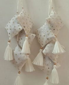 three white pillows with tassels hanging from the side and gold beads on them