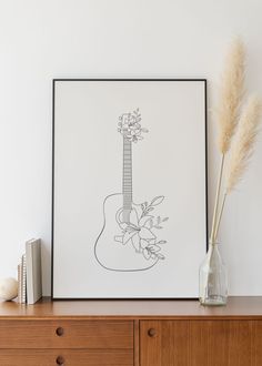 a drawing of a guitar on a wall next to a vase with some flowers in it