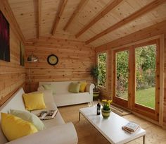 a living room with wood paneling and white couches in front of large windows