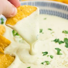 a person dipping tortilla chips into a bowl of dip