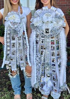 two women in white outfits standing next to each other with silver decorations on their arms