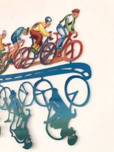 a group of people riding bikes on top of a metal wall hanging sign with bike riders