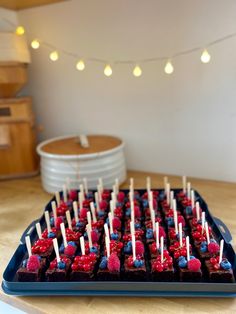 red, white and blue cupcakes with toothpicks in them on a tray