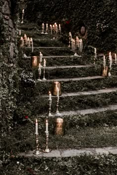 many candles are lit on the steps leading up to an ivy - covered wall and walkway