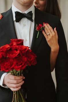 a man in a tuxedo holding roses