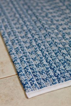 a blue and white rug sitting on top of a floor next to a tile floor