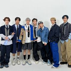 a group of young men standing next to each other in front of a white wall