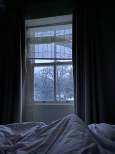 an unmade bed sitting in front of a window