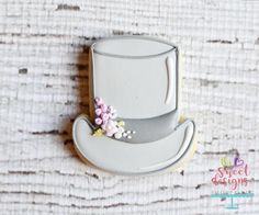 a cookie decorated like a top hat with flowers on the side, sitting on a wooden surface