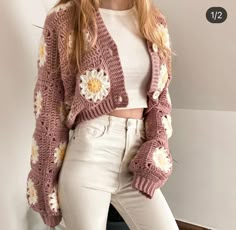 a woman wearing white pants and a pink crochet cardigan with flowers on it