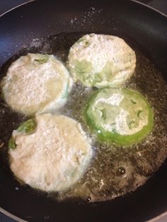 four green peppers cooking in a frying pan