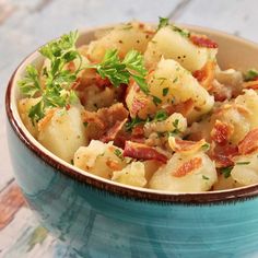 a blue bowl filled with potatoes and bacon