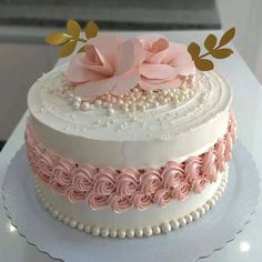 a three layer cake decorated with pink flowers and pearls